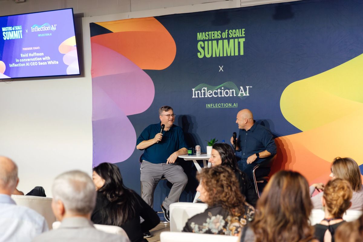 Two speakers in conversation on stage at Masters of Scale Summit x Inflection AI event with audience seated.