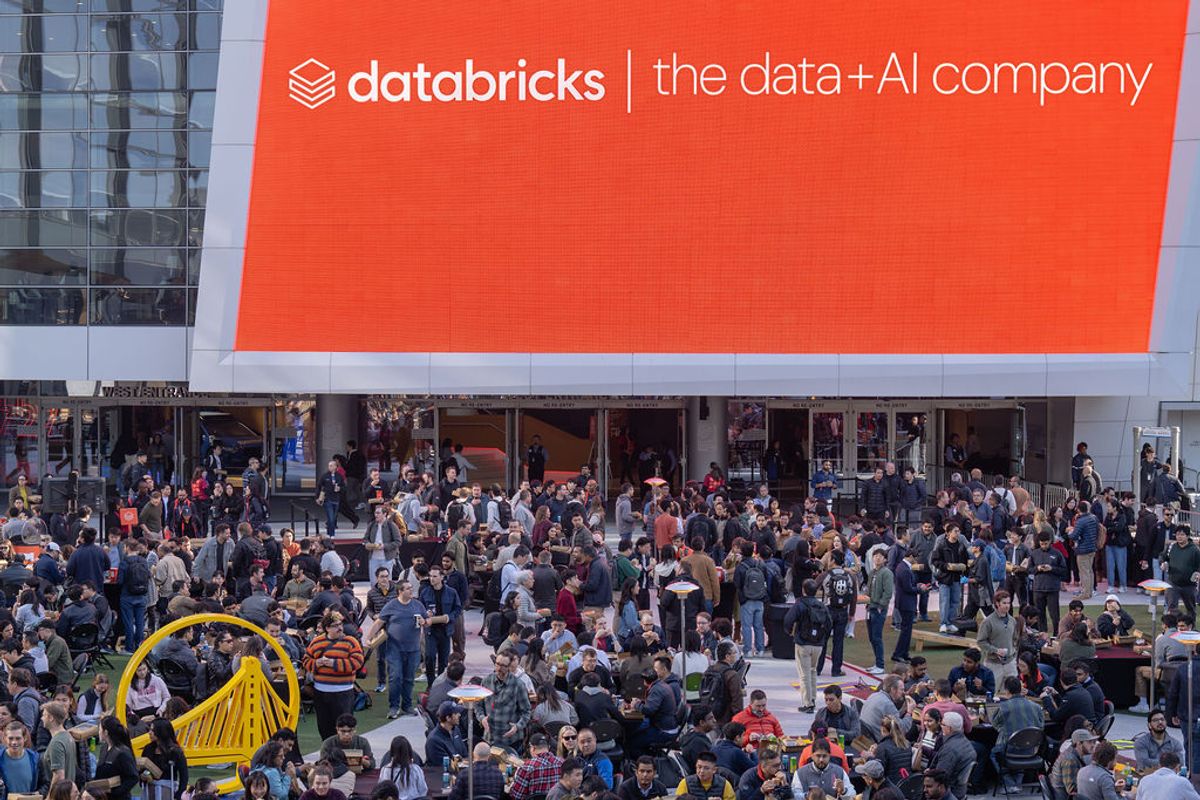 Large crowd of conference attendees gathering in venue lobby area beneath prominent Databricks signage