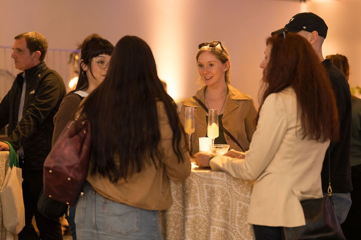Attendees networking and socializing with drinks at an indoor reception event with warm lighting