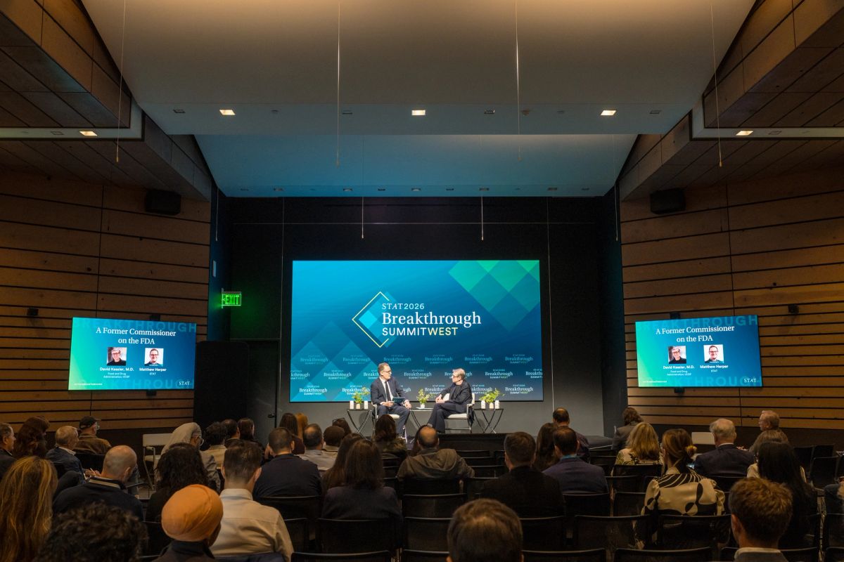 Two speakers on stage presenting to a seated audience in the Commonwealth Club auditorium