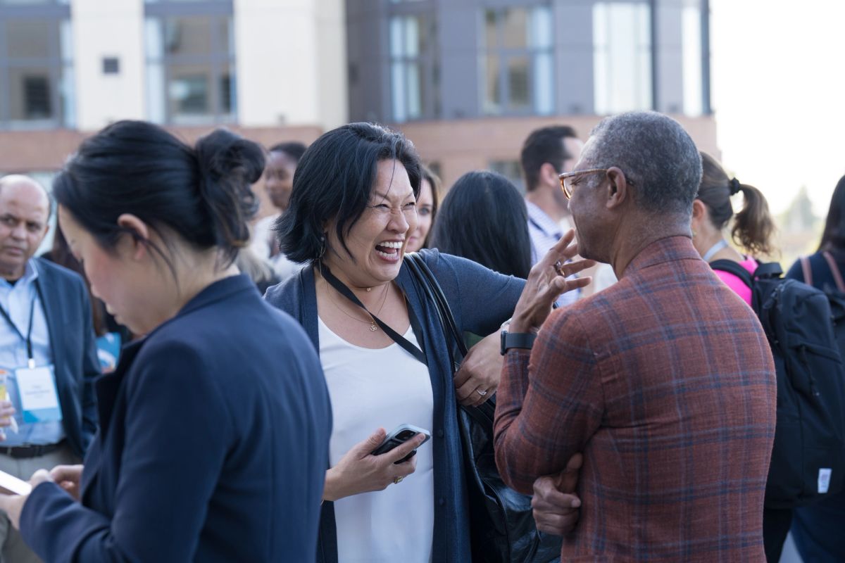 Conference attendees networking and conversing outdoors in front of a building