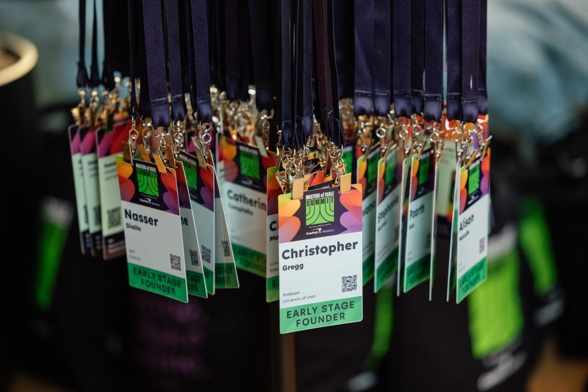Conference name badges with colorful geometric designs hanging on black lanyards, displaying attendee names.