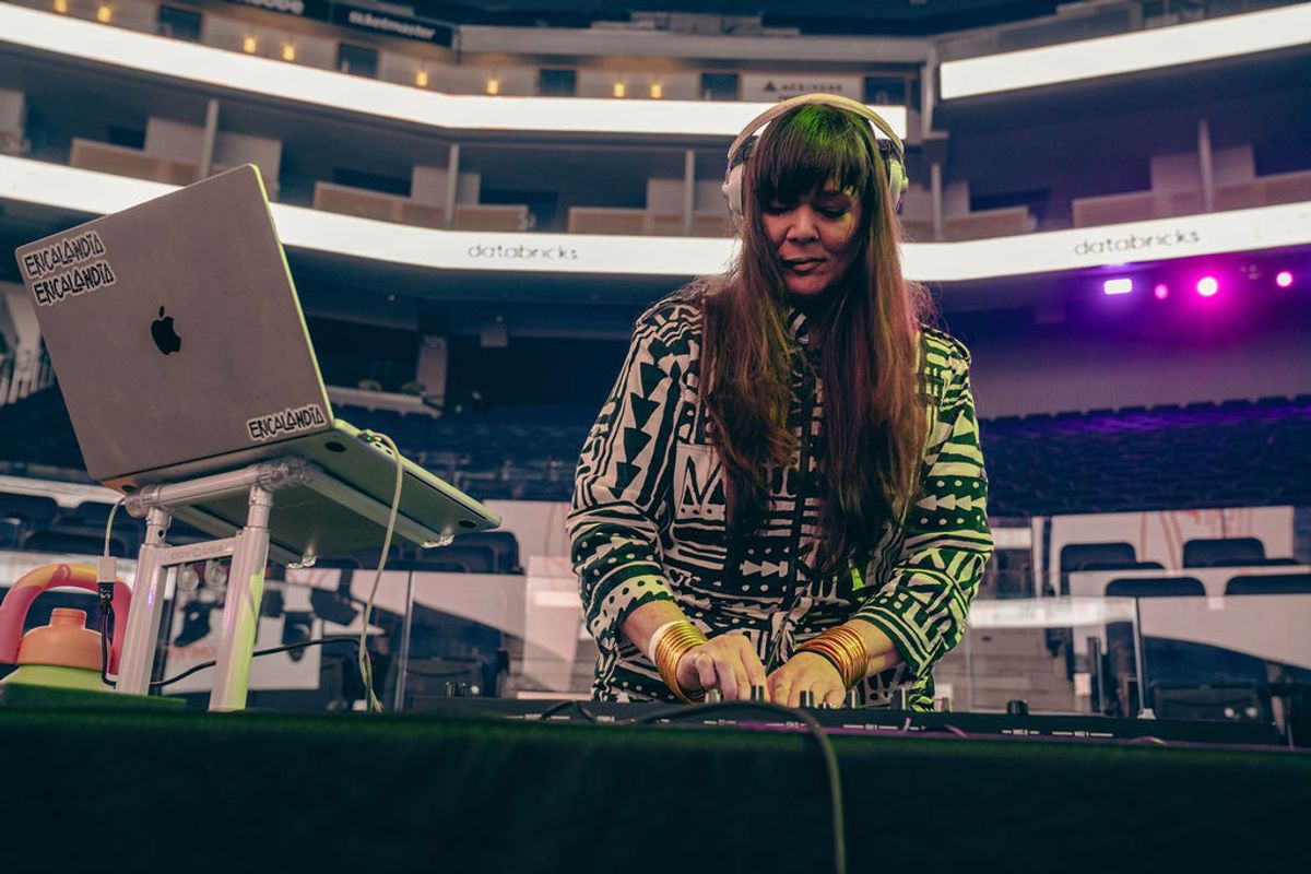 DJ performing with headphones and mixing equipment at multi-level venue with colorful lighting