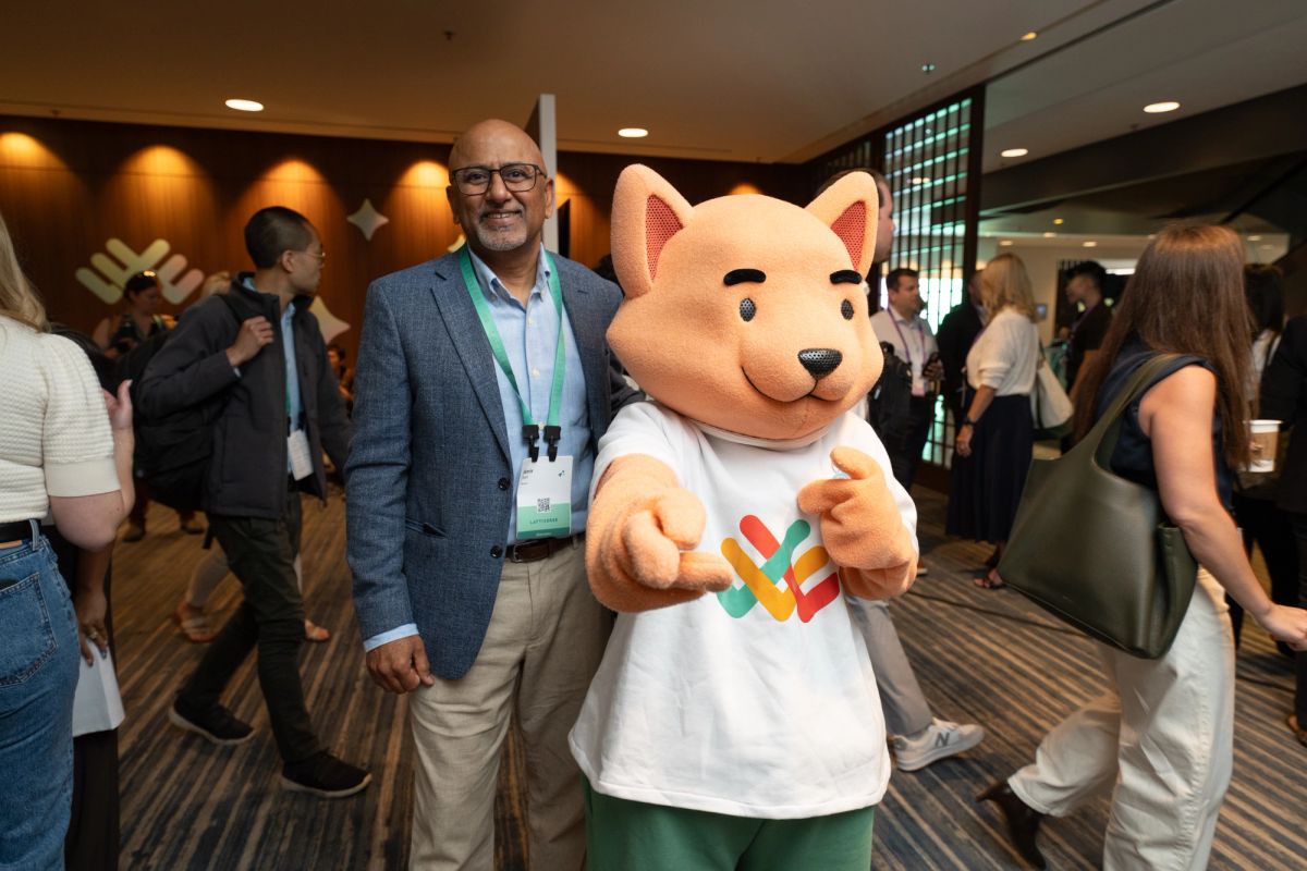Attendee posing with a fox mascot wearing a branded shirt at a conference networking event.