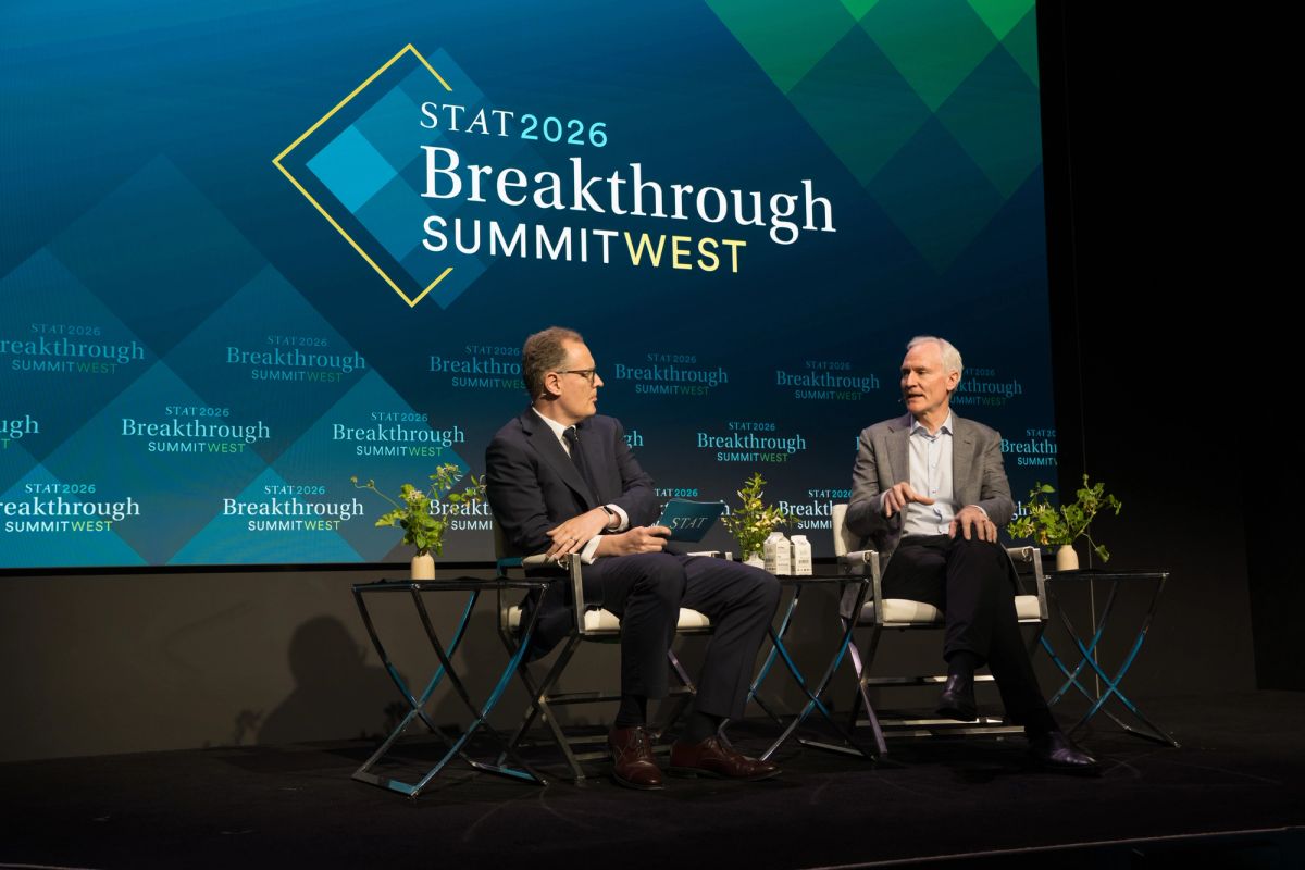 Two men in business attire sitting in chairs on stage having a conversation at STAT2026 Breakthrough Summit.