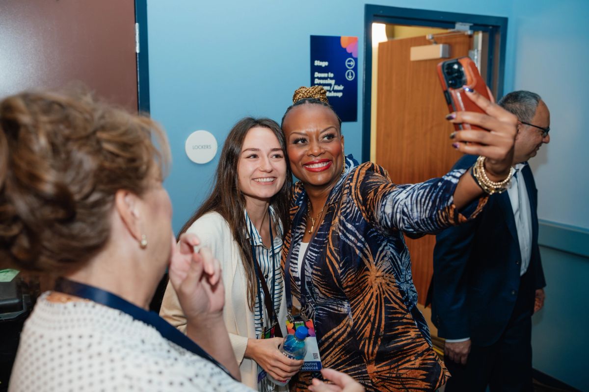 Conference attendees taking a selfie together in a blue-walled venue hallway