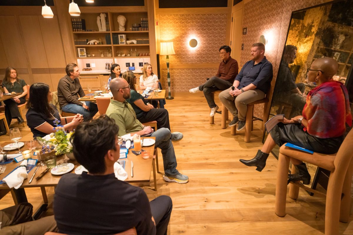 Panel discussion with two speakers seated on stage addressing an audience in a modern room with brick walls