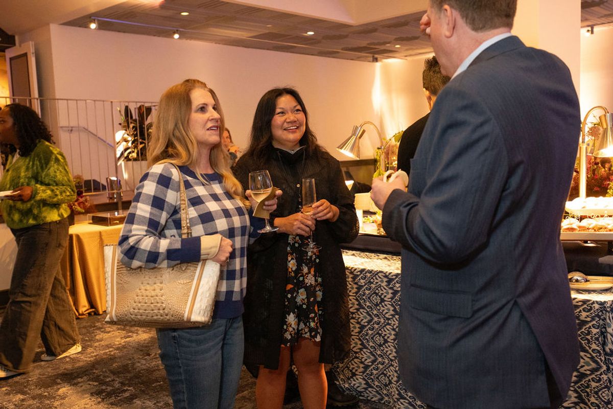 Three professionals networking with wine glasses in an upscale interior space with modern lighting.