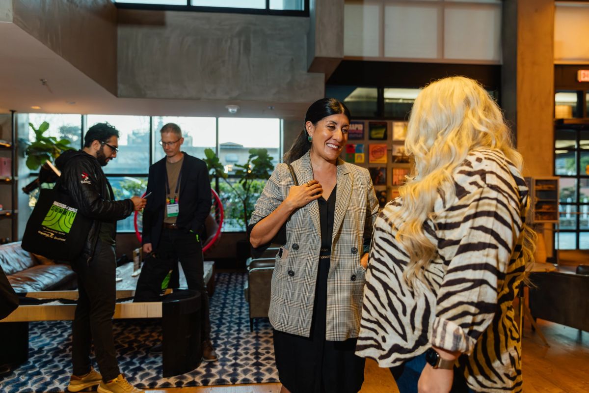 Conference attendees networking in modern lobby with geometric floor tiles and large windows