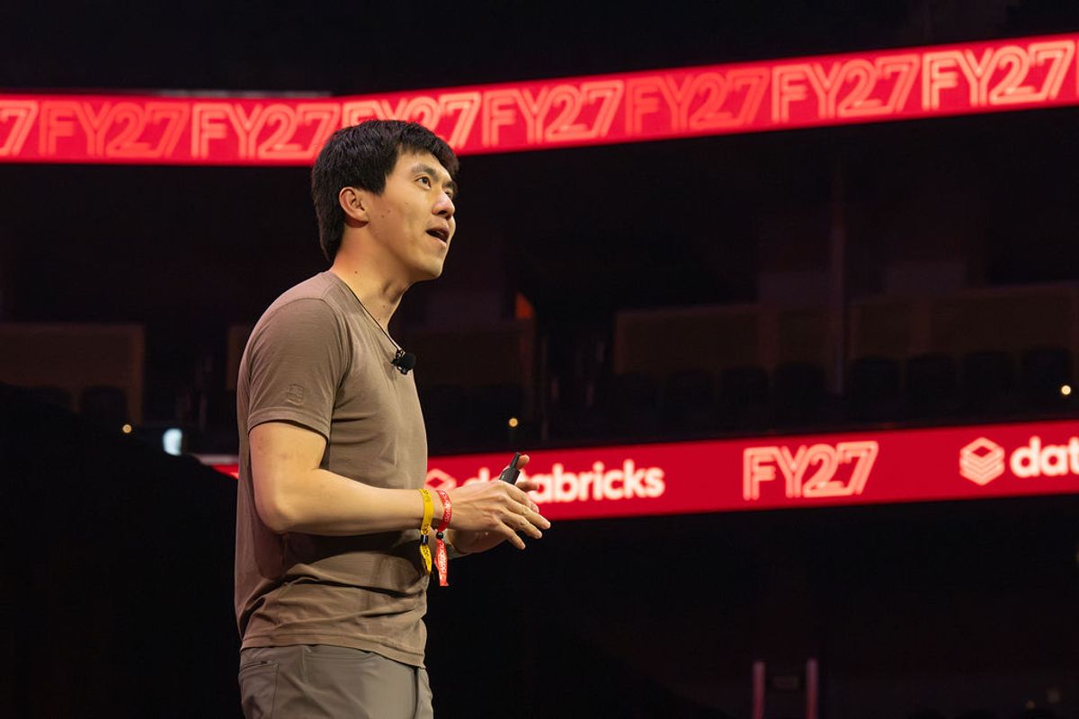 Speaker presenting on stage at Chase Center with FY27 branding visible on red backdrop signage