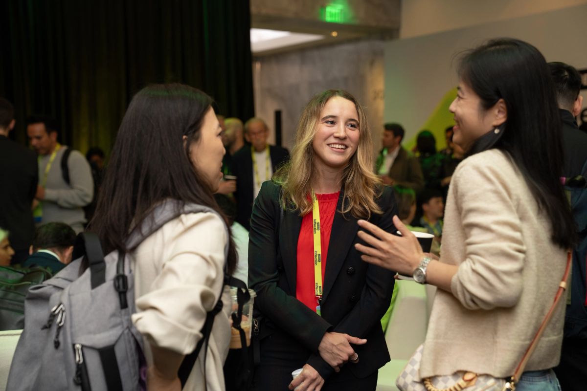 Three attendees networking and conversing at a conference event.