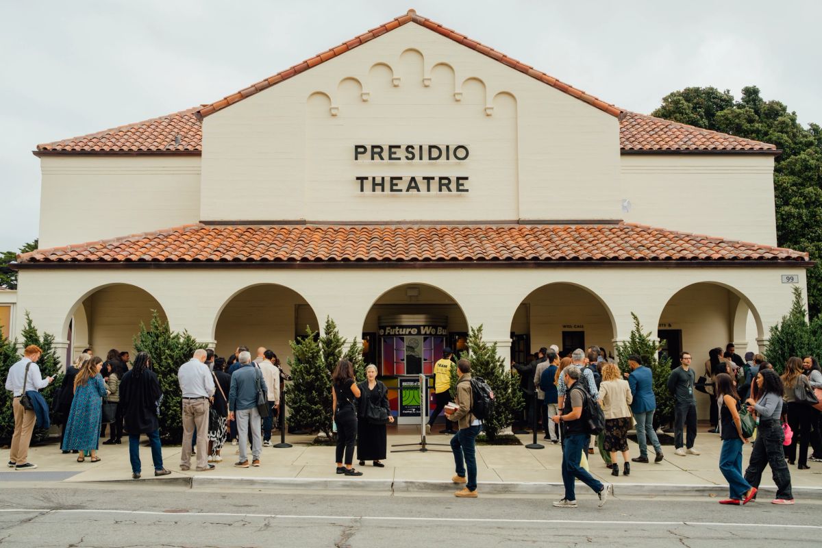 Attendees gather outside Presidio Theatre, a Spanish-style building with arched entrance and tile roof.