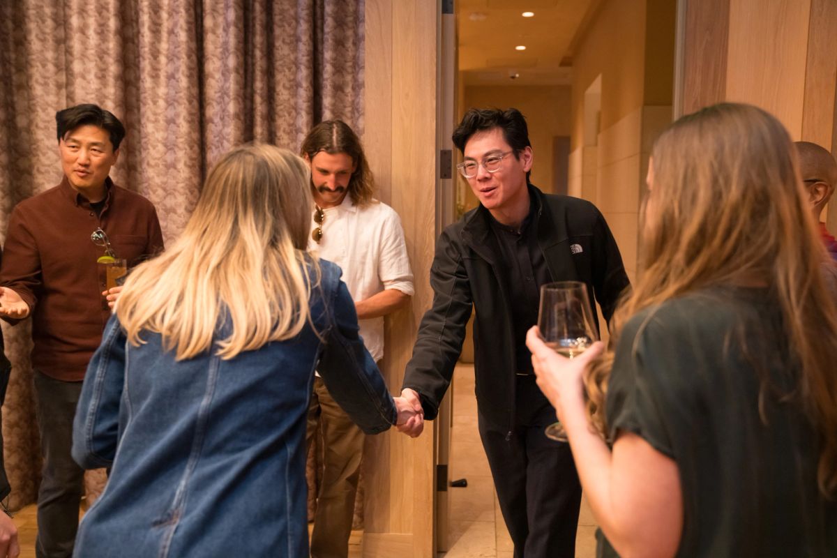 Group of people networking and shaking hands in an indoor event space with curtains and recessed lighting