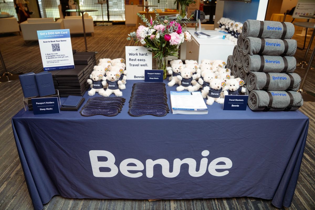 Bennie branded booth displaying travel blankets, teddy bears, sleep masks, and passport holders at a.