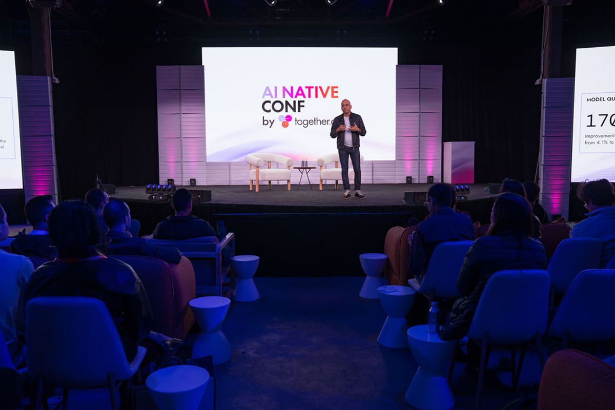 Speaker presenting on stage to seated audience at AI Native Conference event with purple lighting