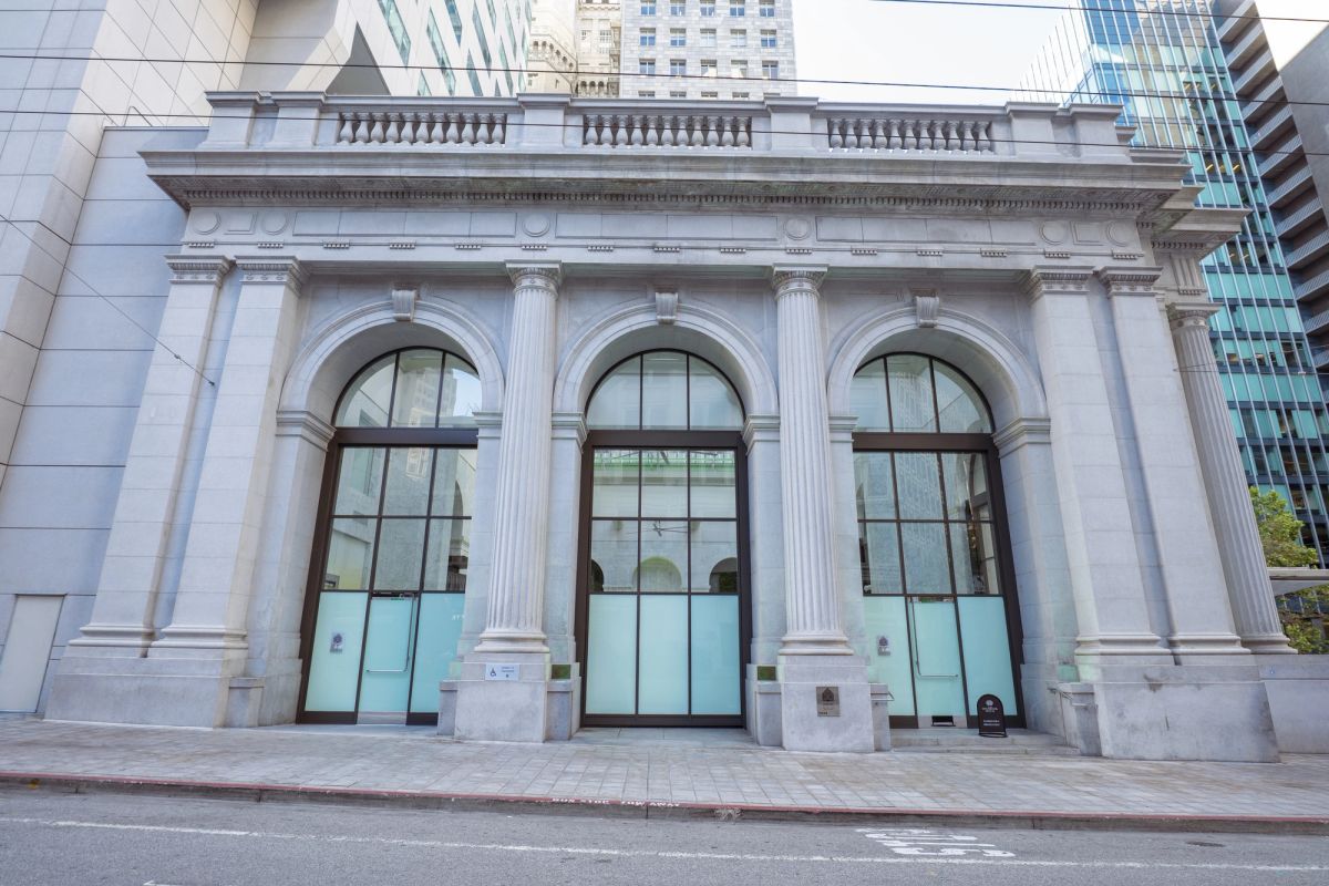 Neoclassical building facade with three arched windows, white columns, and ornate stonework.