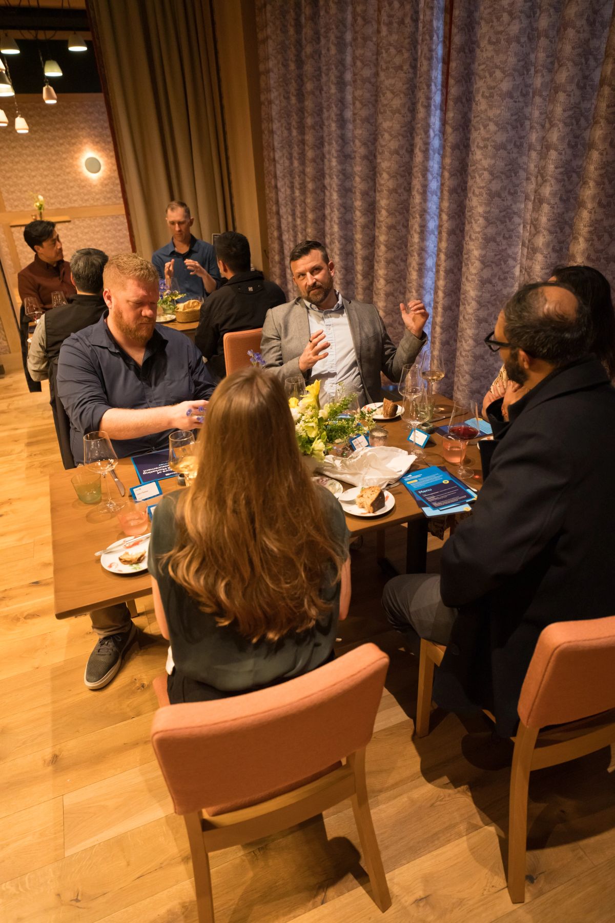 Business professionals networking around tables with food and drinks in a modern restaurant setting
