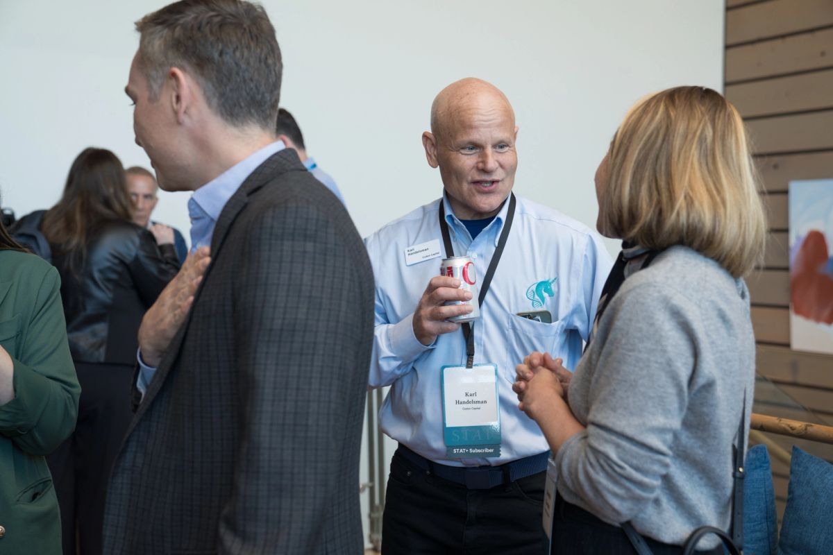 Three professionals networking at a conference, with attendees conversing in a modern venue setting.