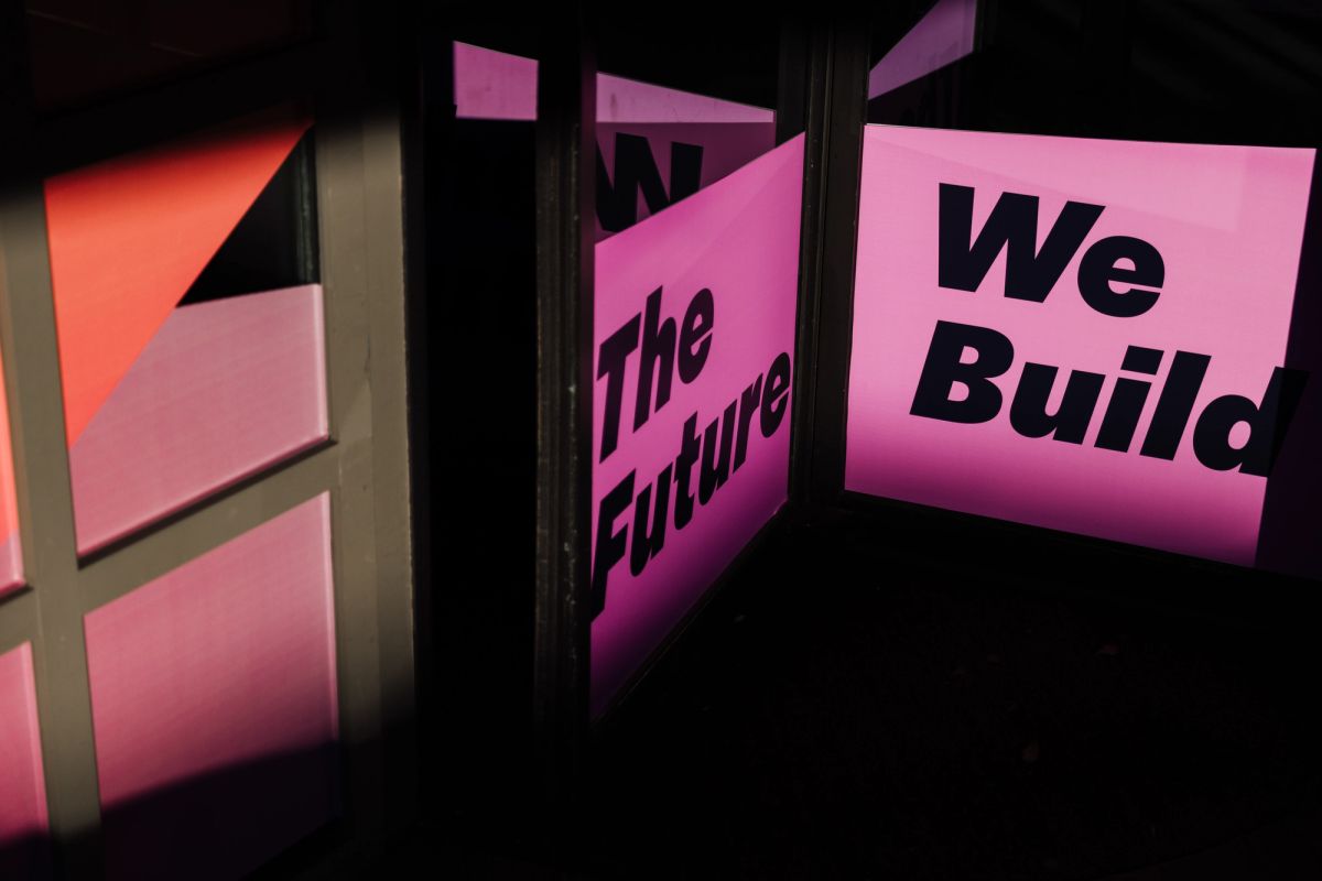Pink illuminated panels display "The Future" and "We Build" text at a conference venue
