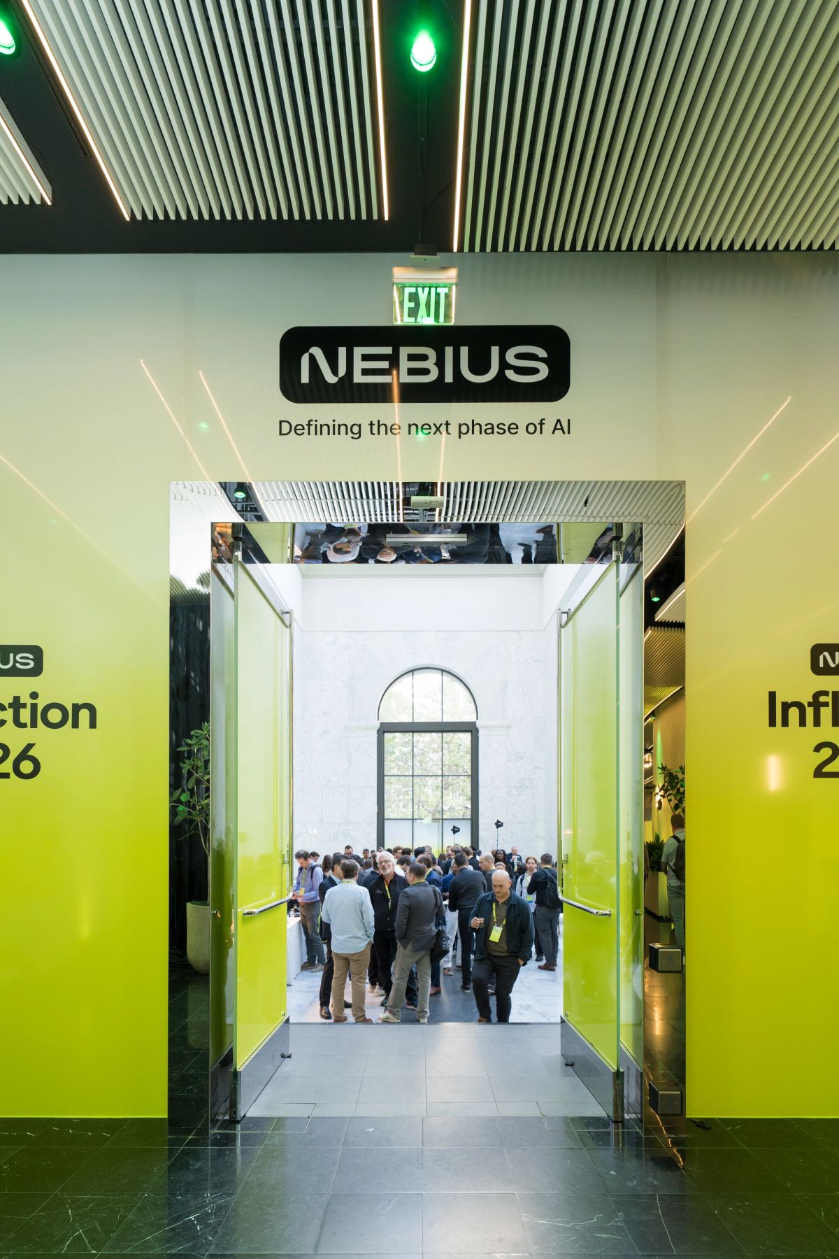 Attendees networking at Nebius "Inflection 26" event inside a venue with green-branded walls.