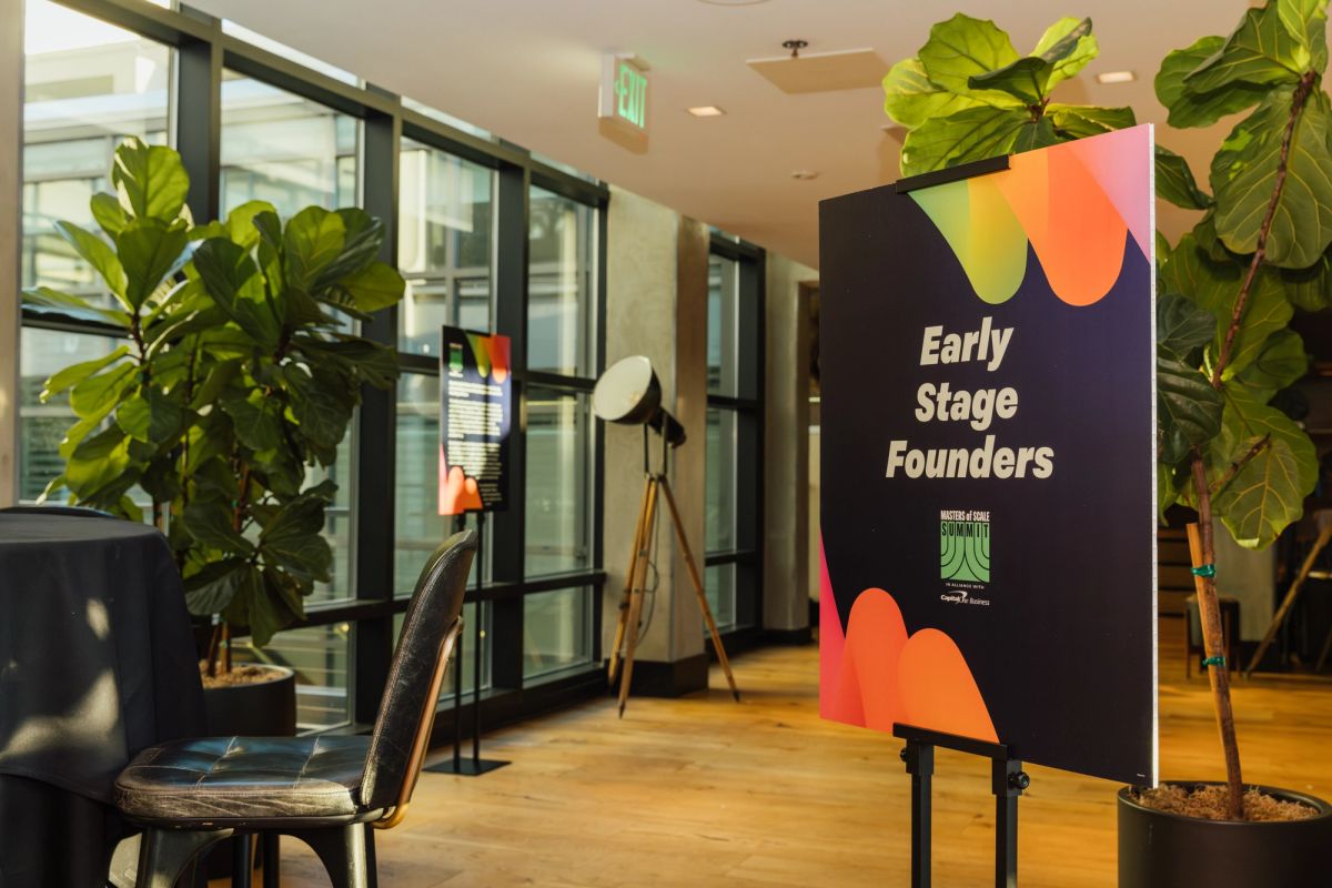 Modern office space with large windows, plants, and "Early Stage Founders" banner on easel stand.