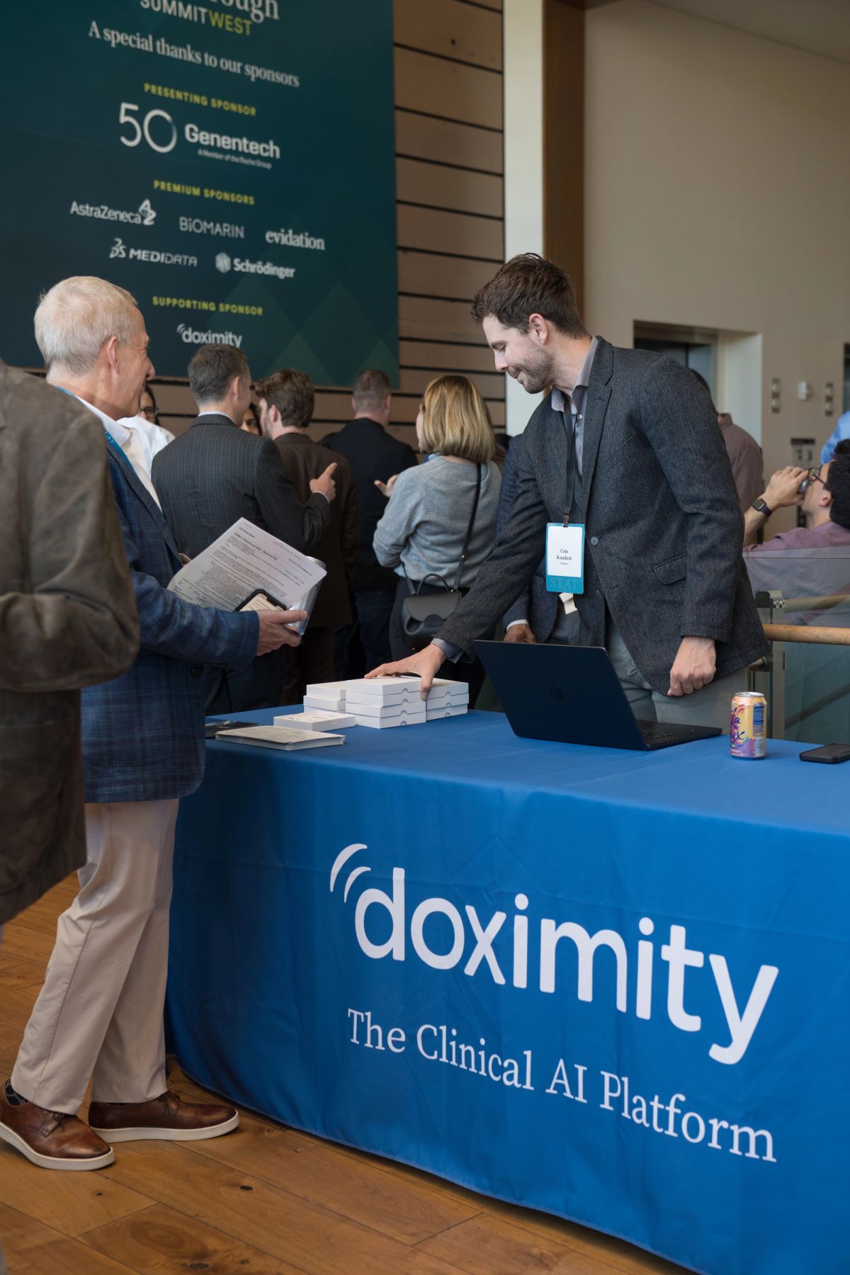 Attendee speaks with representative at Doximity booth displaying "The Clinical AI Platform" at conference.