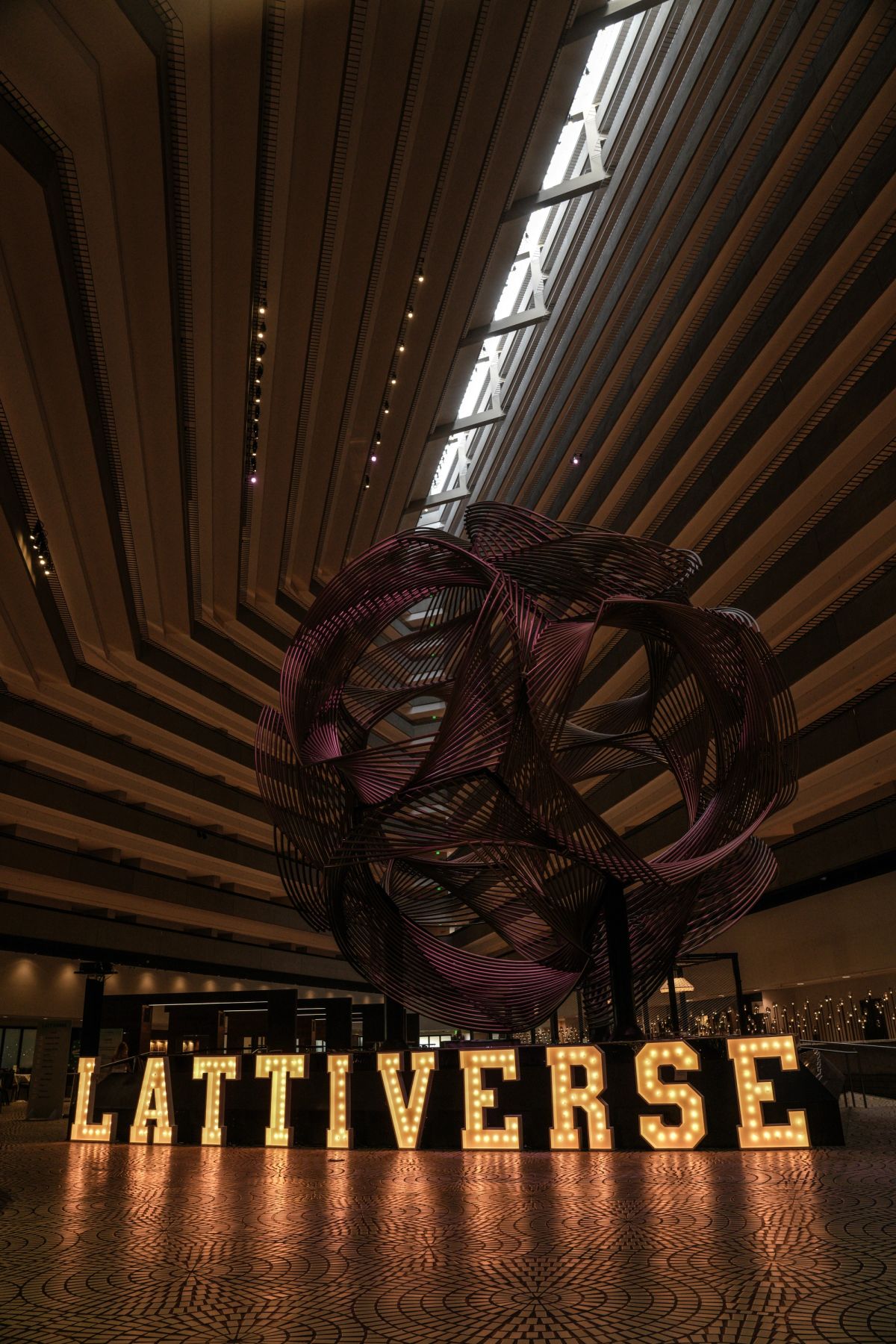 Lattiverse marquee sign with large metal sphere sculpture in Hyatt Regency atrium.