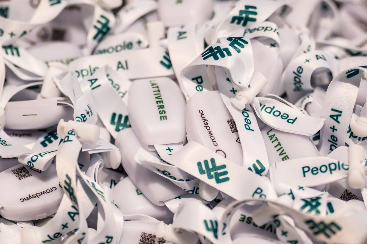 Pile of white event wristbands printed with People + AI and Lattiverse branding logos.