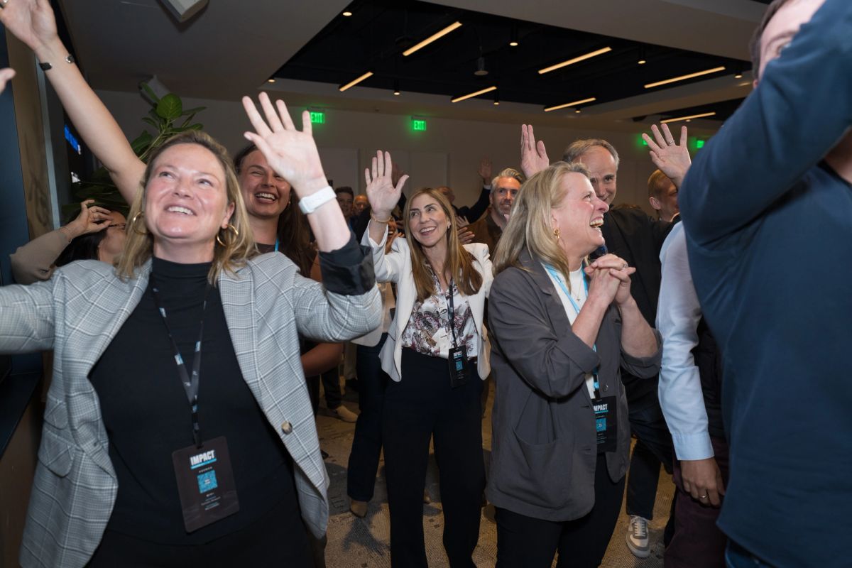 Conference attendees celebrating with raised hands and excited expressions in modern event space