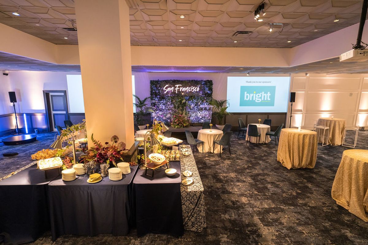 Event space with buffet table, cocktail tables, screens displaying "San Francisco" and "bright" logos