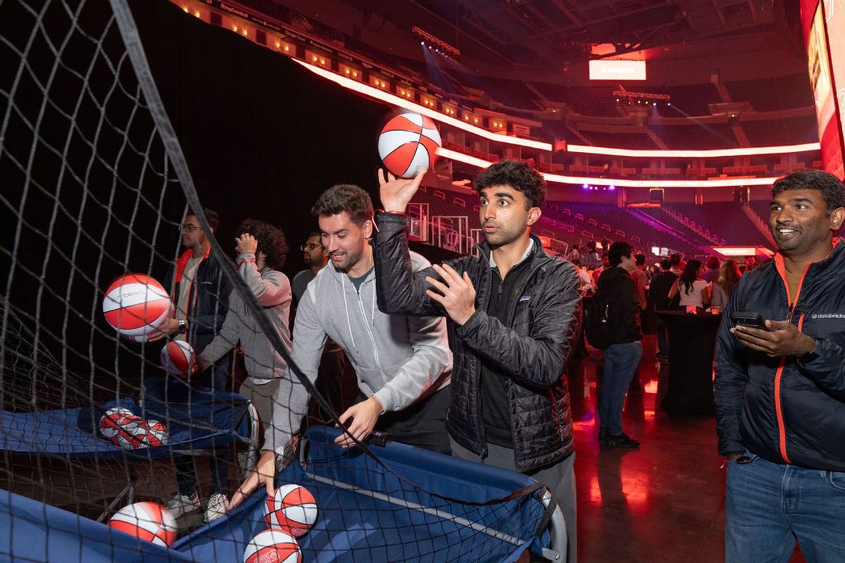 Conference attendees playing basketball shooting game at indoor venue with red lighting