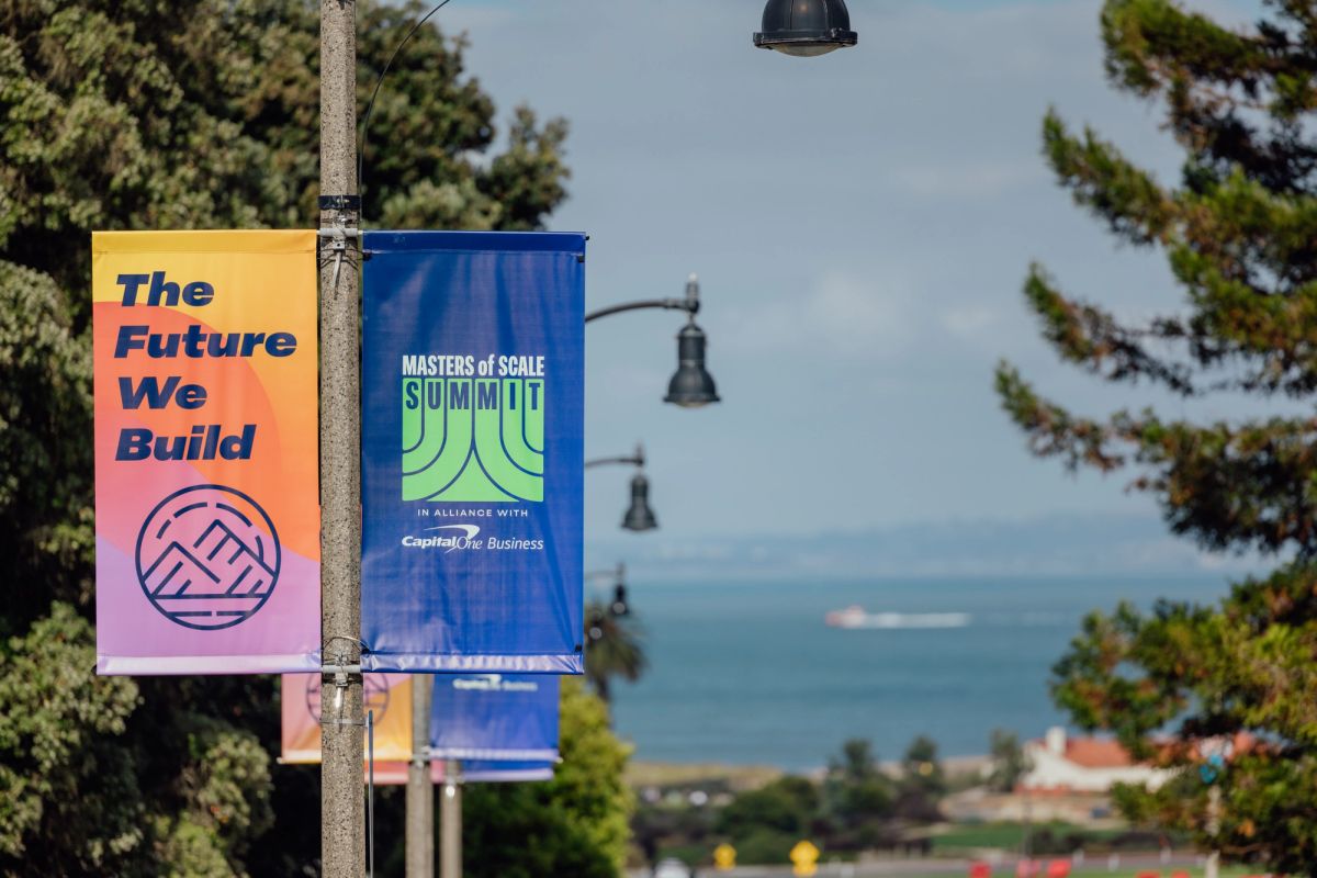 Street banners reading "The Future We Build" and "Masters of Scale Summit" hang on lamp post with trees and.
