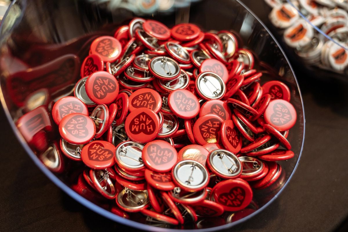 Bowl of red "Humans" pin buttons at a conference.