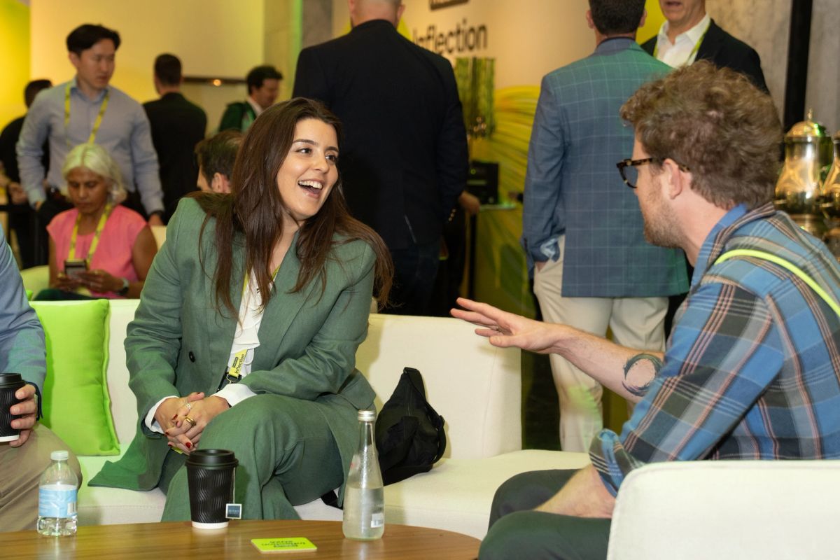 Two attendees networking and laughing on a couch at a conference.