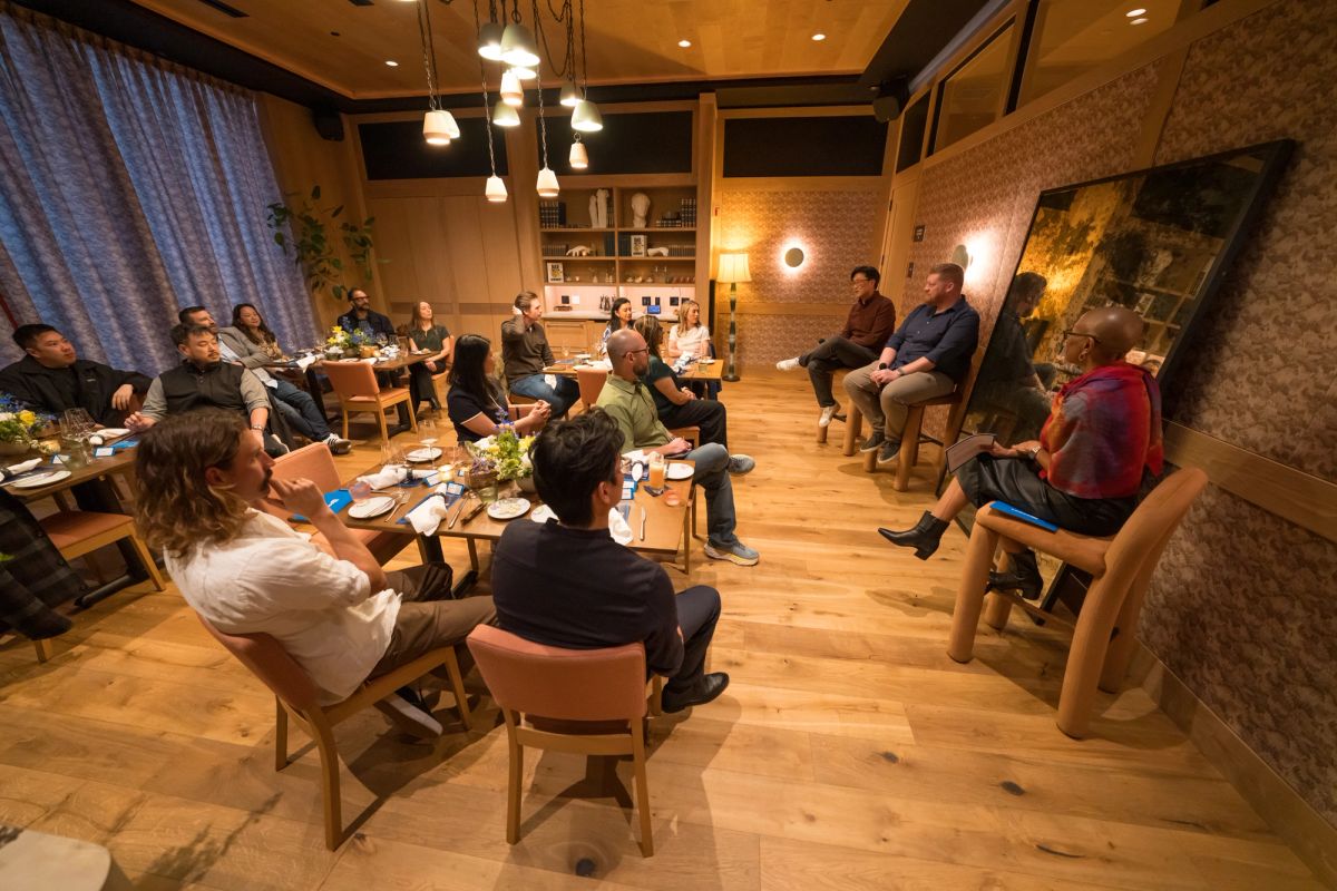 Panel discussion with speakers and audience members seated in chairs in a modern wood-paneled room