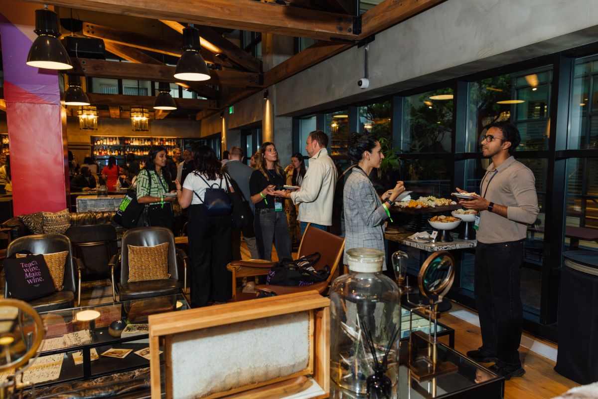 Conference attendees networking at evening reception in modern restaurant with exposed beams and large windows