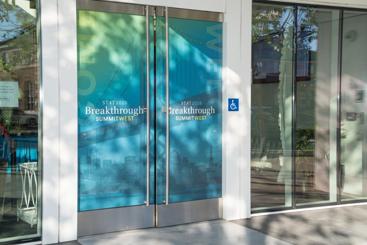 Glass entrance doors with blue STAT Breakthrough Summit West signage at the Commonwealth Club San Francisco