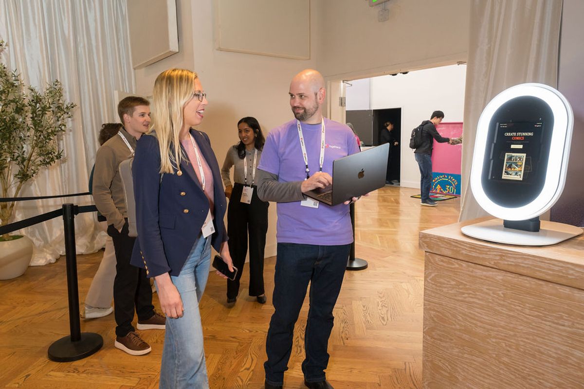 Conference attendees view a demonstration of an oval-shaped tech device with LED lighting at an indoor event.