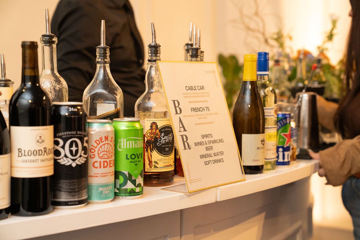 Bar setup with various bottles of wine, cider, and spirits, plus cocktail dispensers at networking reception