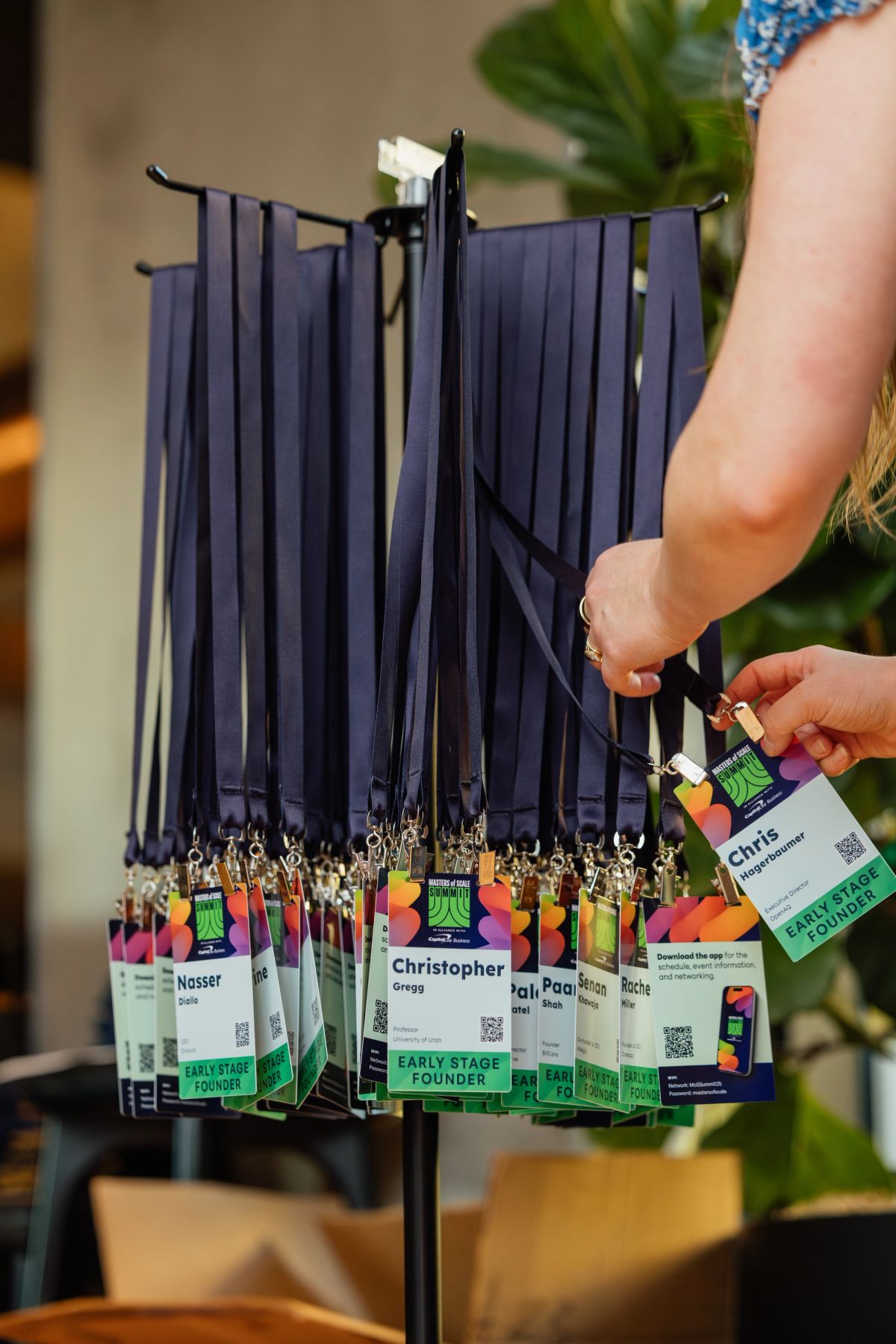 Person selecting name badge from display rack with colorful lanyards at conference registration area