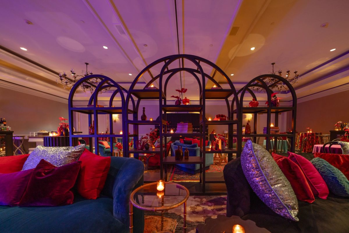 Luxurious lounge with colorful velvet pillows, ornate arched frames, and purple ambient lighting