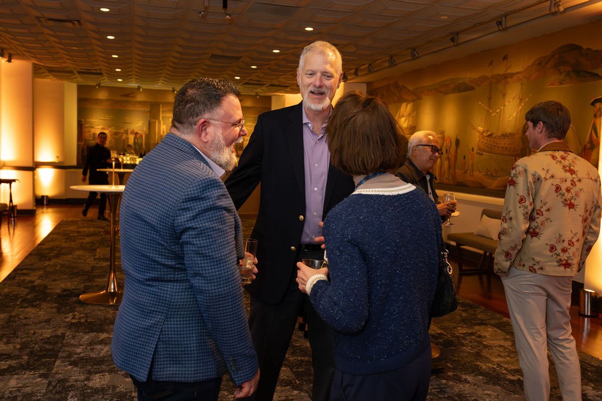 Business professionals networking and conversing at an indoor reception event in an elegant venue.