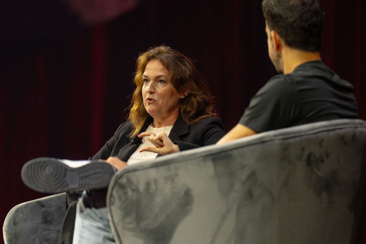 Two people in conversation seated on stage chairs during a conference event