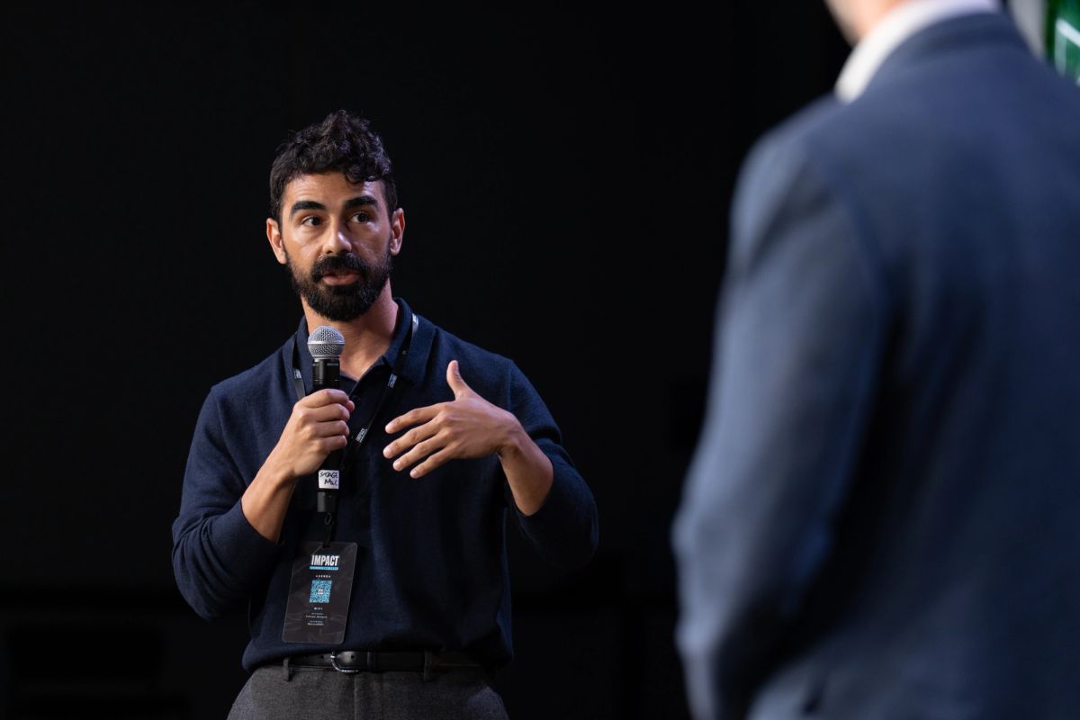 Speaker with microphone gesturing while presenting to another person in business attire at conference event