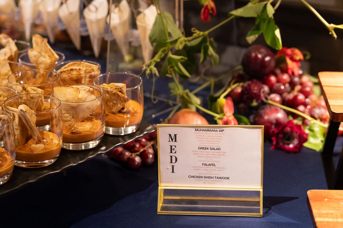 Mediterranean food buffet with appetizers in glasses, grapes, cheese, and menu card at networking event