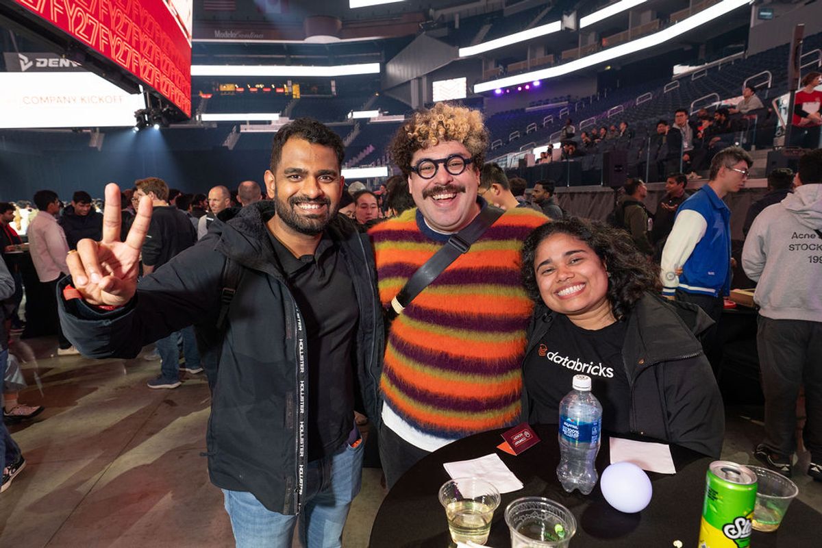Three people pose together at a networking event, with one person making a peace sign gesture