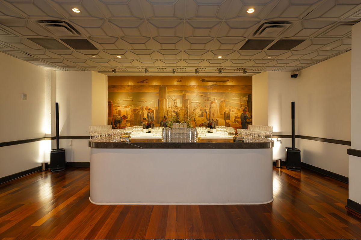 Elegant reception room with curved white bar, wooden floors, hexagonal ceiling, and illuminated mural backdrop
