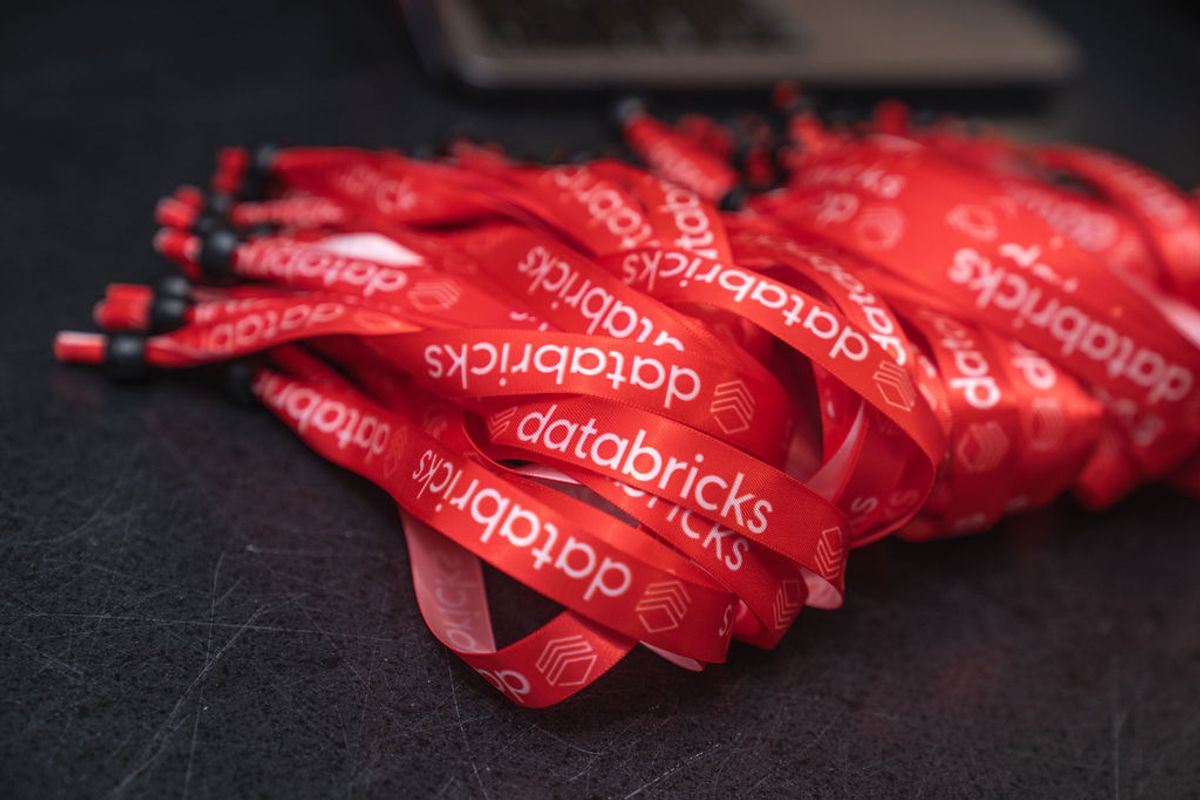 Red Databricks lanyards piled on a dark surface at a conference event