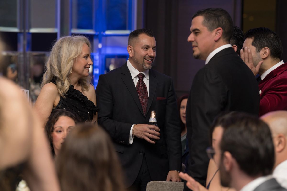Attendees in formal attire networking and conversing at an upscale evening gala event