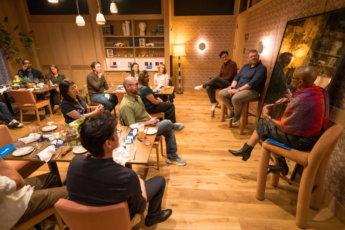 Group of people sitting in chairs arranged in a circle for a panel discussion in a modern room with wooden.